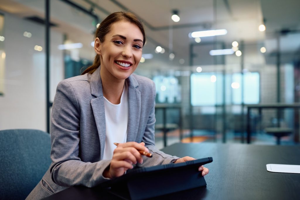 Female insurance agent smiling while working on a touch tablet