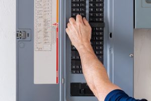 Resetting tripped breaker in residential electricity power panel.