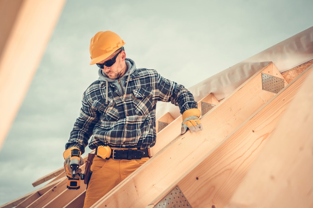 Roofing contractor working on wood frame of new house's roof