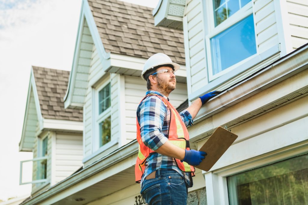 Home inspector standing on ladder to inspect roof