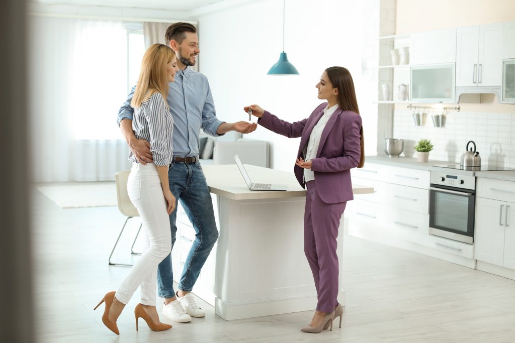 Female real estate agent giving house key to couple inside of their new home