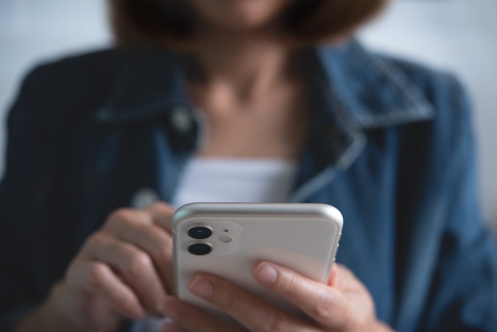 Close up of young woman's hands holding and using mobile smart phone