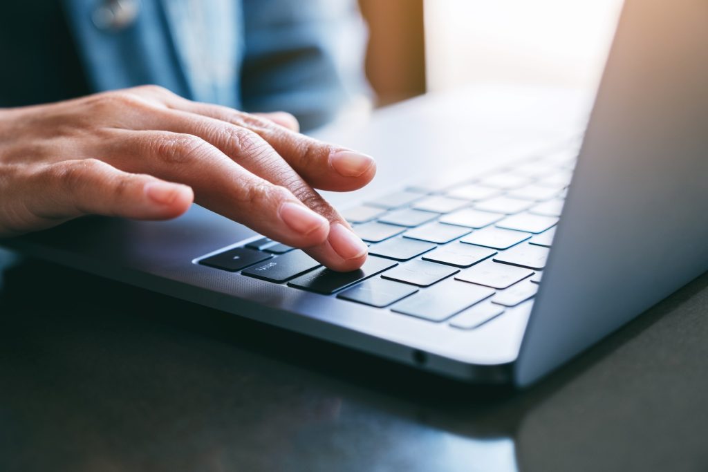 Closeup image of a man's finger pressing on the enter button of a laptop computer