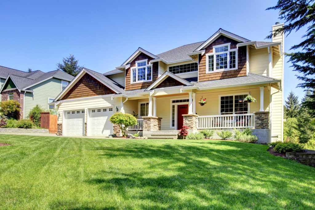Large American house with red door and two white garage doors.