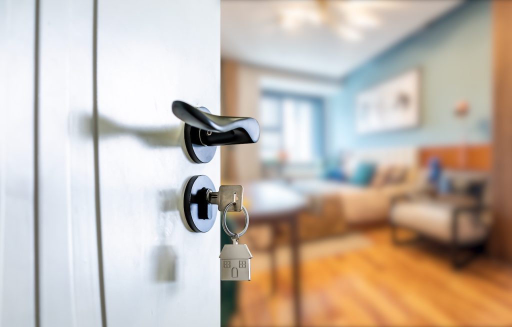 Close up of doorknob with key in lock leading into a house